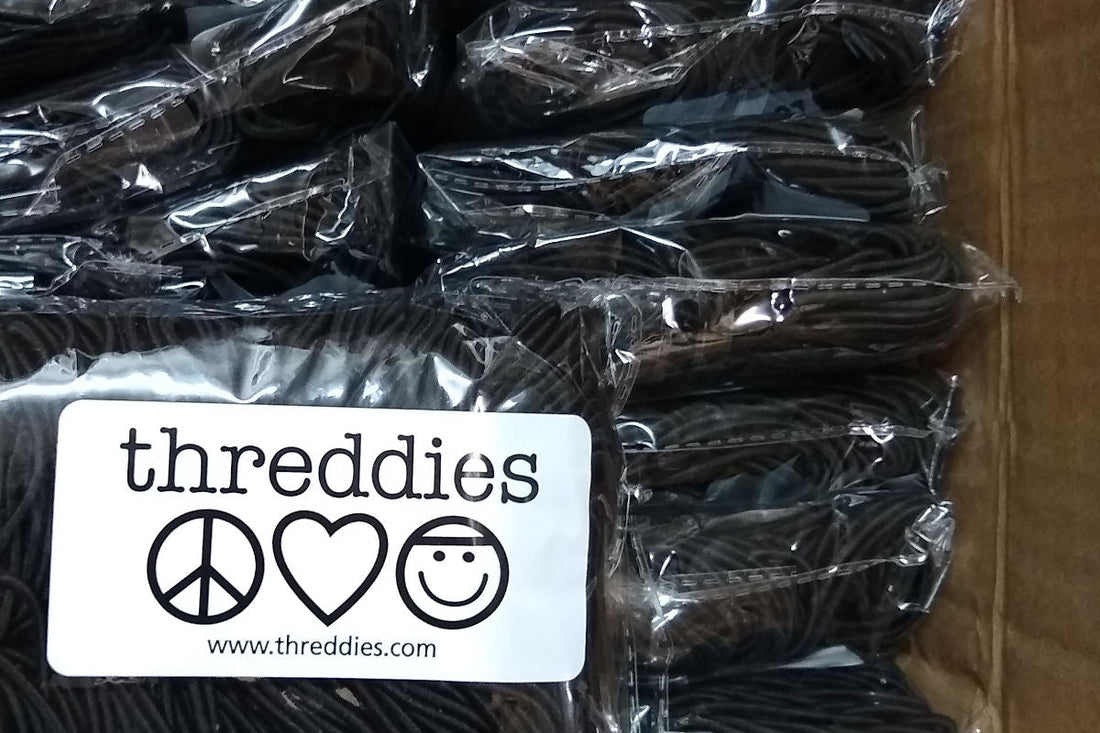 a cardboard box filled with black hair ties, sold wholesale by threddies